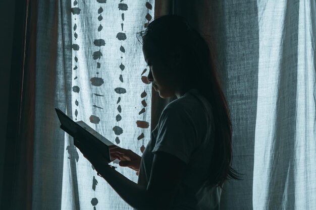 Vrouw die een boek leest bij het raam