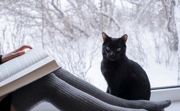 Vrouw die een boek leest naast een zwarte kat