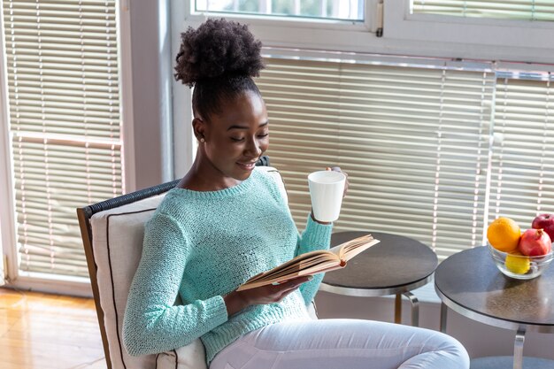 Vrouw die een boek op een stoel leest