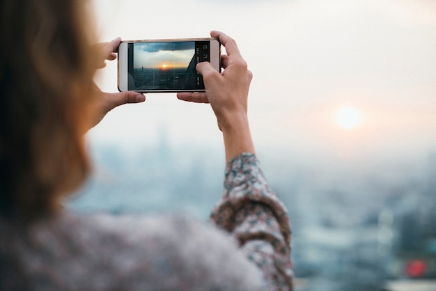 Vrouw die een foto van de zonsondergang neemt