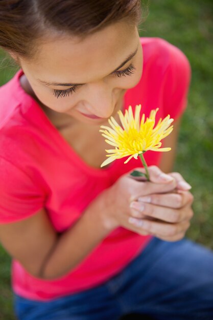 Foto vrouw die een gele bloem ruikt
