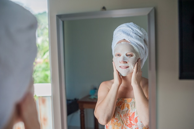 vrouw die een gezichtsmaskerblad toepast