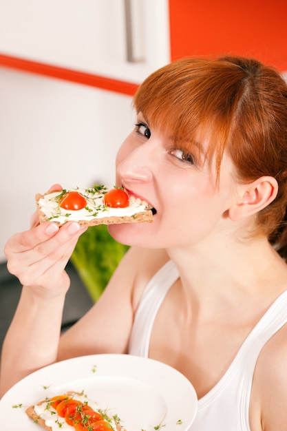 Vrouw die een gezonde toost met tomaat en kaas eet