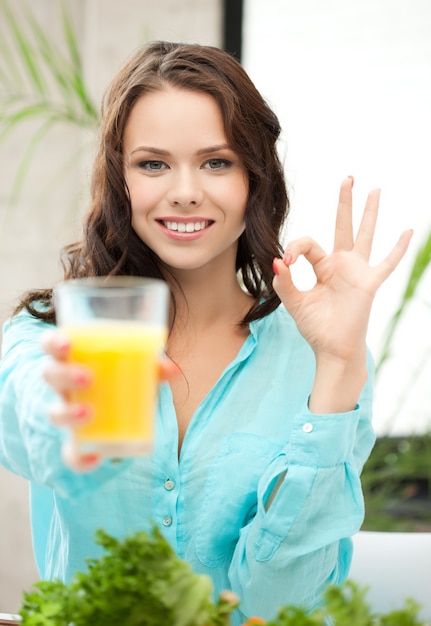 Vrouw die een glas sinaasappelsap vasthoudt en een goed teken toont