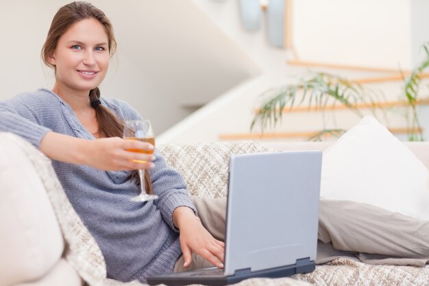 Vrouw die een glas wijn heeft terwijl het gebruiken van haar laptop