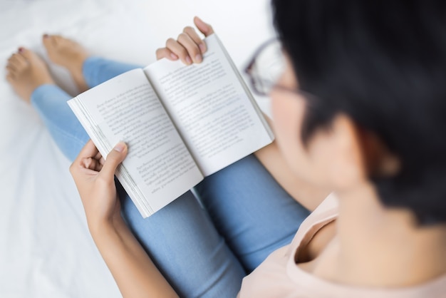 Vrouw die een goed boek leest terwijl op haar bed