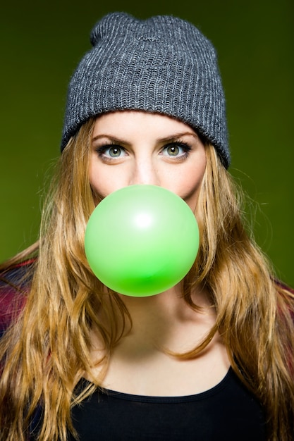 Vrouw die een groene kauwgom met de mond