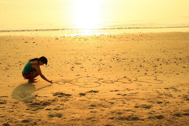 Vrouw die een hartsymbool in zand trekt