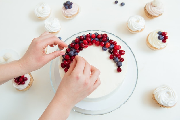 Vrouw die een heerlijke cake met bosbessen verfraait