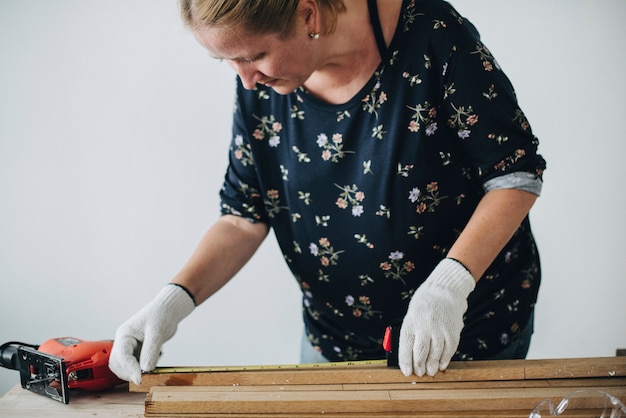 Vrouw die een houten plank meet