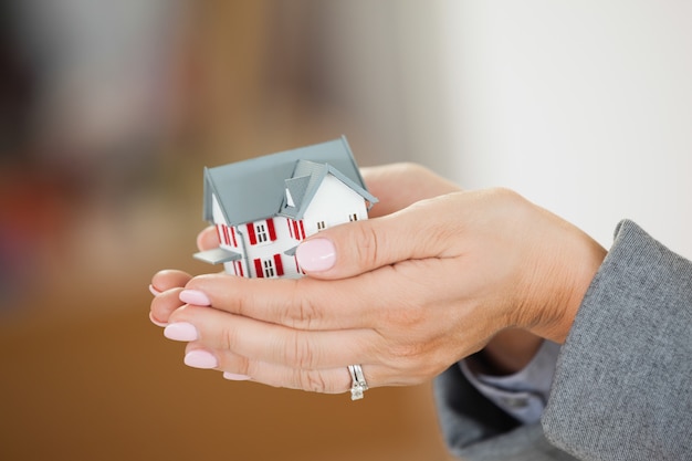 Vrouw die een huis in haar handen houdt