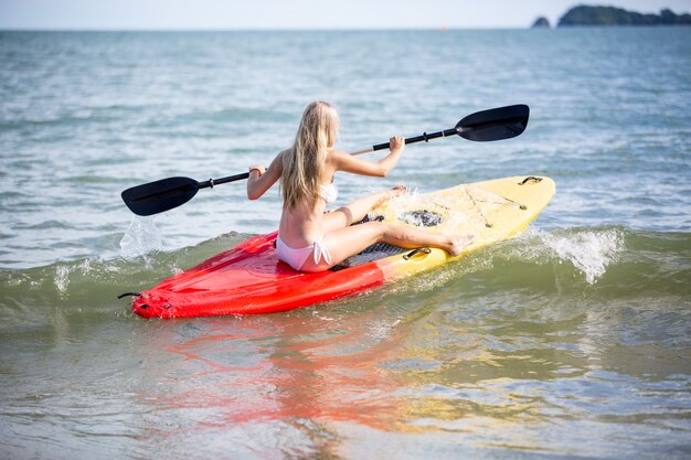 Vrouw die een kajak paddelt door het tropische strand. Kajaktocht in Phuket, Thailand