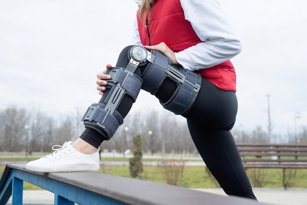 Vrouw die een kniebrace of orthese draagt na een beenoperatie die in het park traint