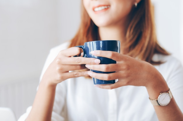 Vrouw die een kop van koffie houdt.