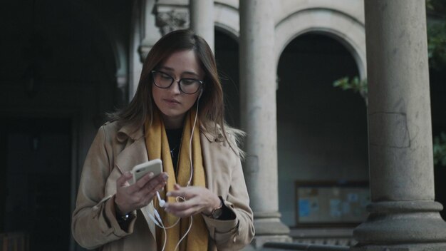 Vrouw die een koptelefoon opdoet Zakenvrouw luisteren naar muziek in oordopjes buiten