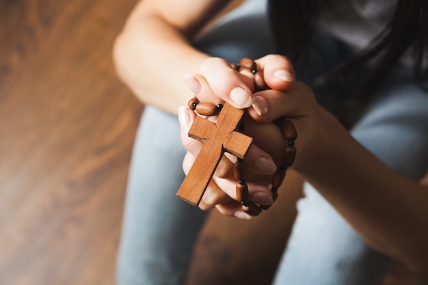 Vrouw die een kruis vasthoudt en op de grond bidt