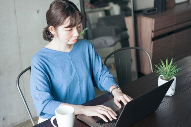 Vrouw die een laptop bedient op de tafel in de kamer