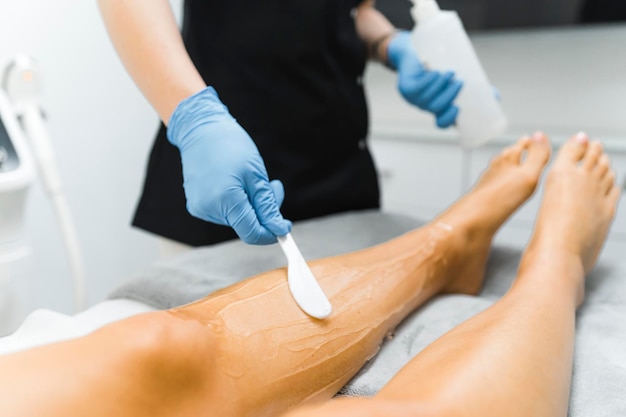 Vrouw die een laserbeenontharing krijgt in een professionele salon