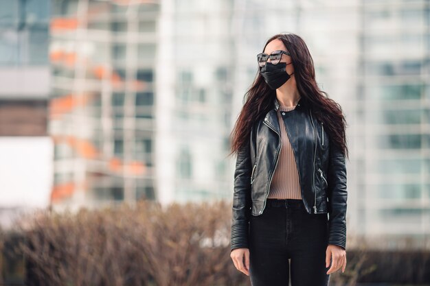 Vrouw die een masker draagt op een achtergrond van een modern gebouw,