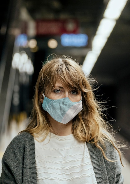 Vrouw die een masker draagt tijdens het wachten op de trein tijdens de pandemie van het coronavirus