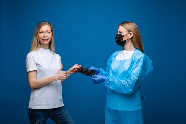 Vrouw die een masker van een arts met omhoog duim neemt.