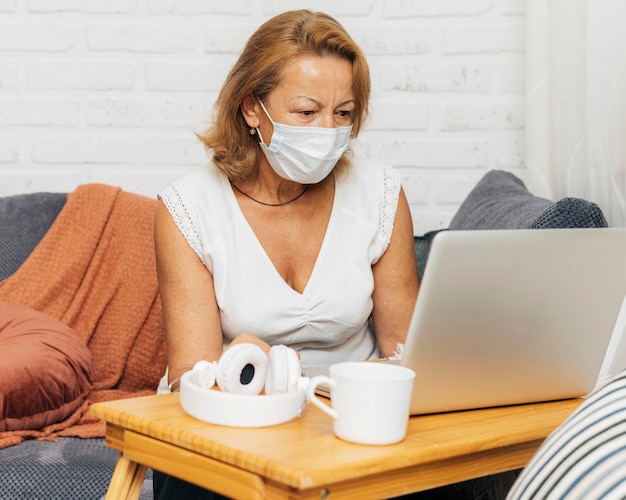 Foto vrouw die een medisch masker draagt tijdens een videogesprek