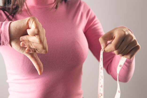 Vrouw die een meetlint vasthoudt en duim naar beneden laat zien