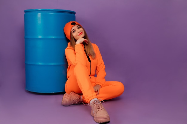 Foto vrouw die een modieuze oranje overall op violette achtergrond draagt