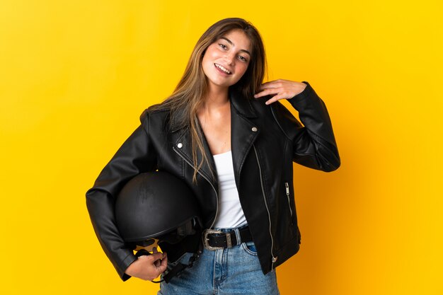 Vrouw die een motorfietshelm houdt die bij het gele lachen wordt geïsoleerd