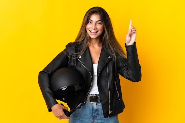 Vrouw die een motorhelm houdt die op gele muur wordt geïsoleerd die een geweldig idee benadrukt