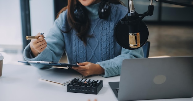 Vrouw die een podcast opneemt op haar laptop met een koptelefoon en een microscoop Vrouwelijke podcaster die een audio podcast maakt vanuit haar thuisstudio