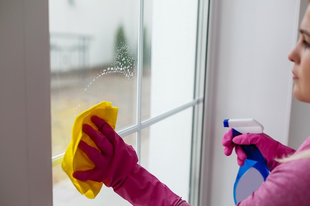 Vrouw die een raam schoonmaakt met gele doek