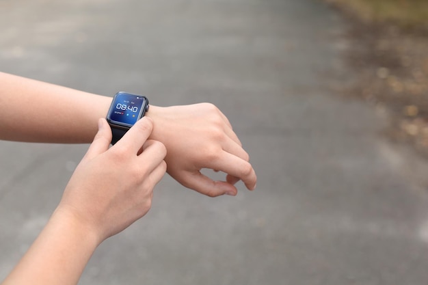 Vrouw die een slim horloge gebruikt om de tijd of hartslag buitenshuis te controleren