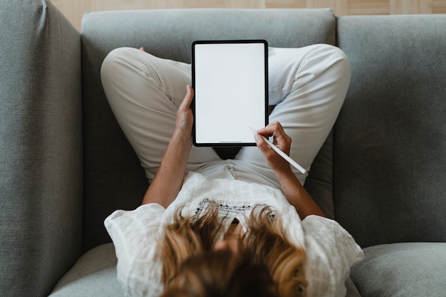 Vrouw die een stylus gebruikt met een digitale tablet tijdens de quarantaine van het coronavirus thuis