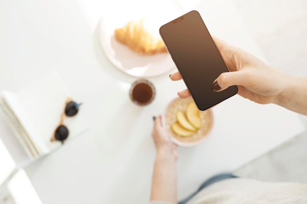 Foto vrouw die een telefoon gebruikt om een foto van haar maaltijd te maken