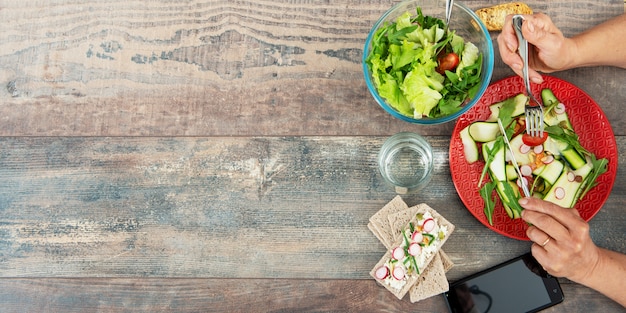 Vrouw die een veganistsalade eet. Diverse groenten op hout