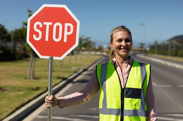 Vrouw die een veiligheidshesje draagt en een stopbord vasthoudt