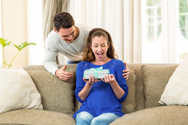 Vrouw die een verrassingsgift van de mens thuis ontvangt