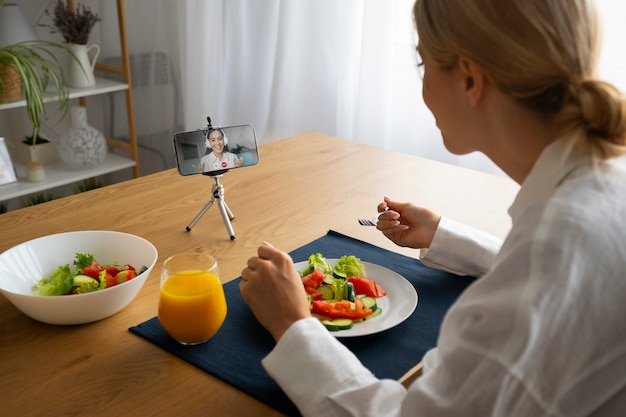 Foto vrouw die een videogesprek voert terwijl ze eet