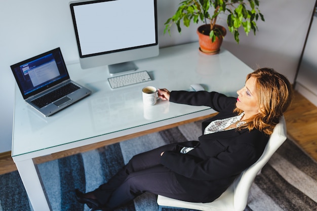 Vrouw die en aan muziek in modern bureau ontspannen luisteren