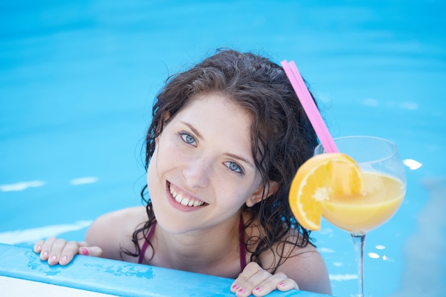 Vrouw die en een cocktail ontspannen drinken bij zwembad