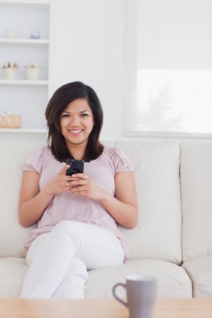 Vrouw die en een telefoon glimlacht houdt