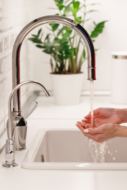 Vrouw die en haar handen wast schoonmaakt onder stromend leidingwater