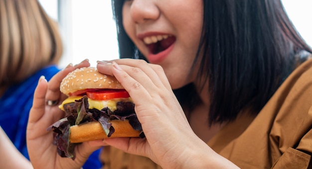 vrouw die en hamburger glimlacht houdt