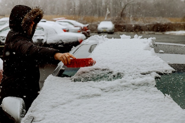 Vrouw die en sneeuw schept verwijdert uit haar auto, geplakte sneeuw