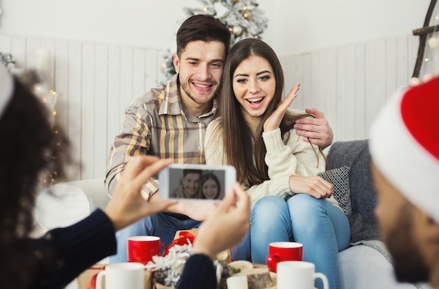 Vrouw die foto's maakt van een gelukkig stel op kerstavond thuis