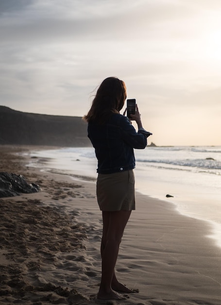 Vrouw die foto van zonsondergang op het strand neemt