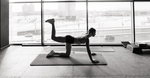 Vrouw die geavanceerde yoga beoefent op mat tegen een groot raam