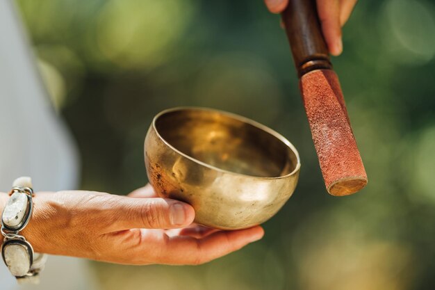 Foto vrouw die geluidstherapie in de natuur uitvoert met een tibetaanse zangbak