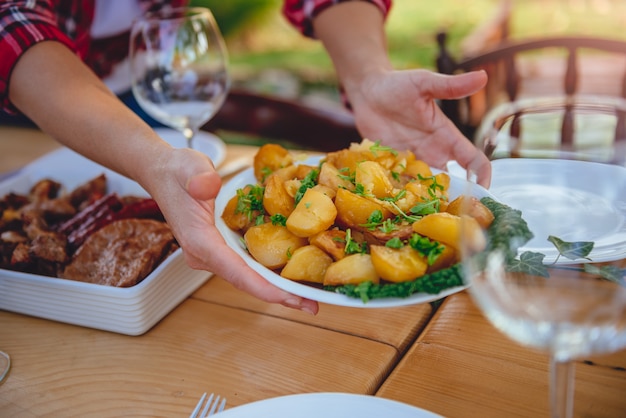 Vrouw die geroosterde aardappels op eettafel dienen